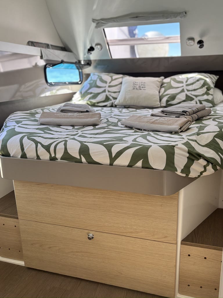 A double cabin aboard Zephyr, bed made and porthole open