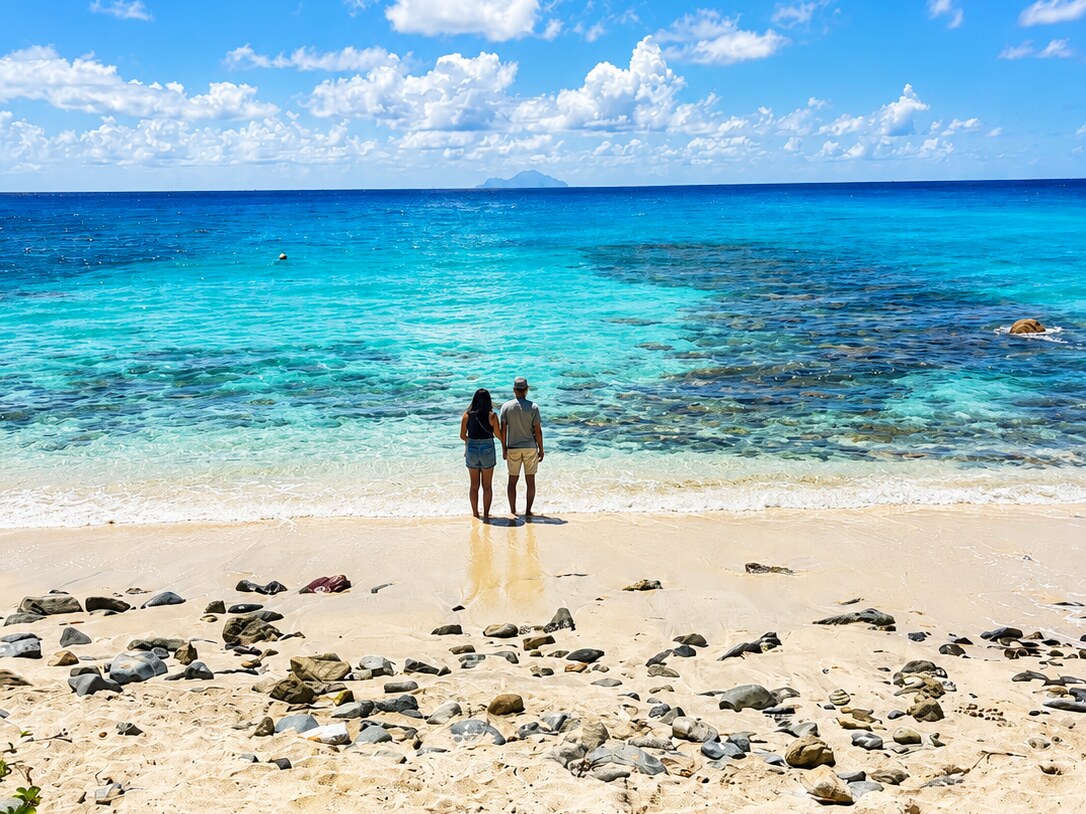 A couple on a deserted beach, the island of Saba on the horizon